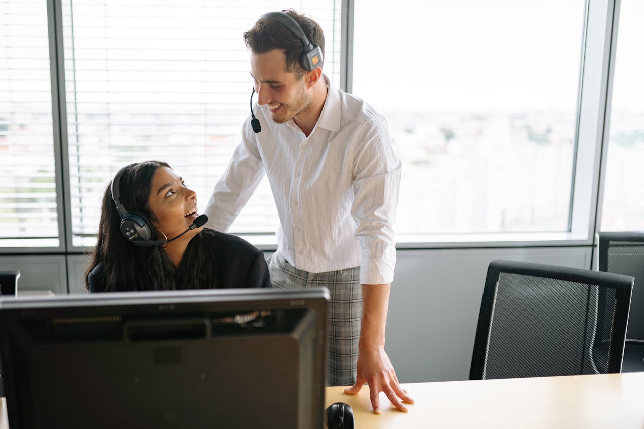 heros-img Smiling colleagues wearing headsets working together at a call center in a modern office setting.